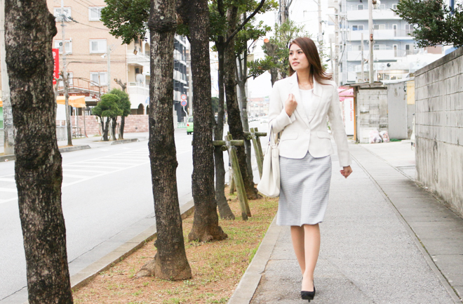 歩道を歩くレディススーツを着た女性